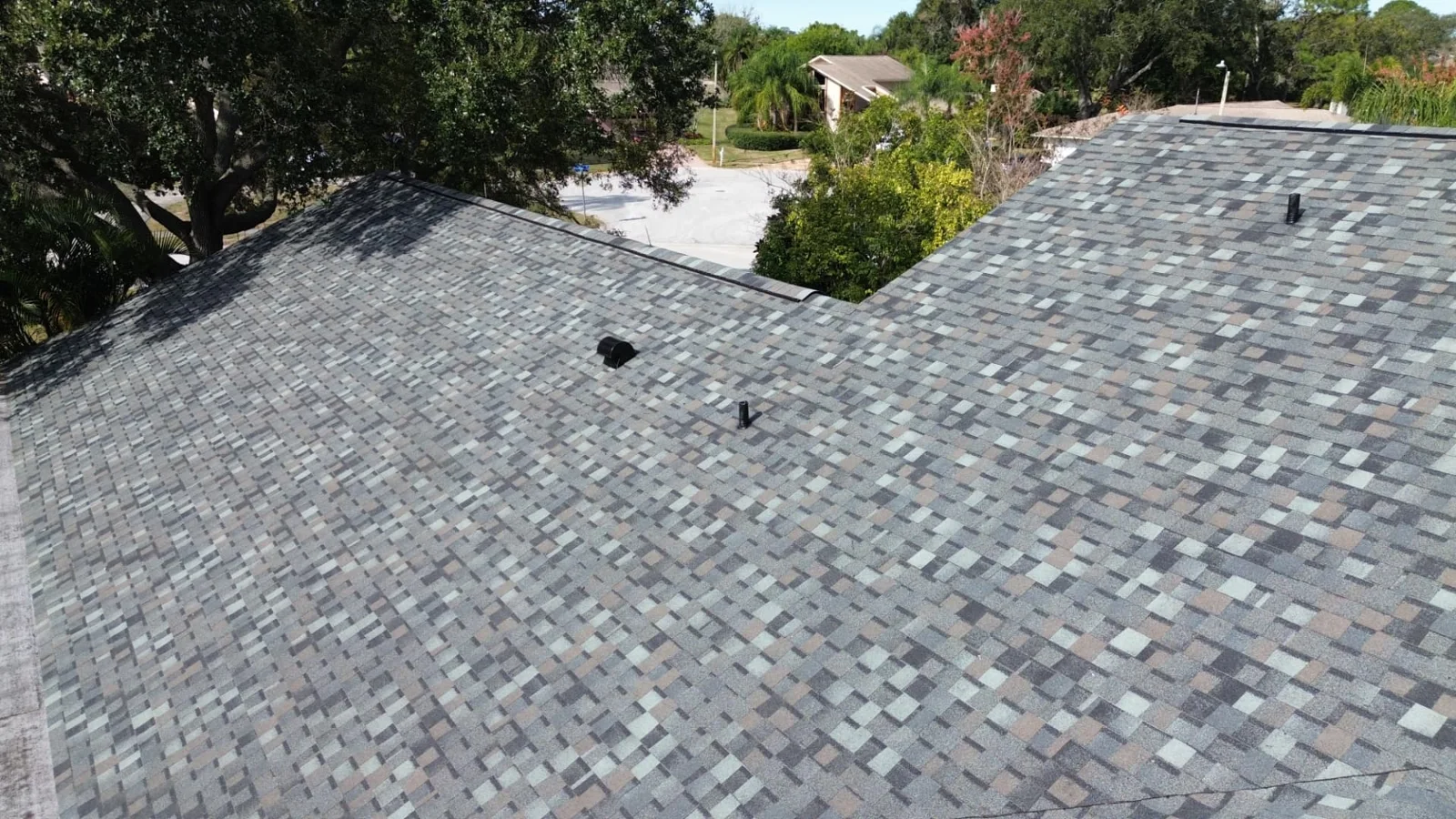 Drone view of an asphalt shingle roof surrounded by trees